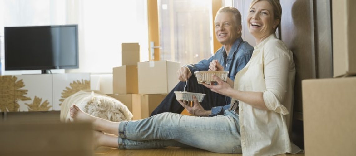 Couple eating take out food near moving boxes